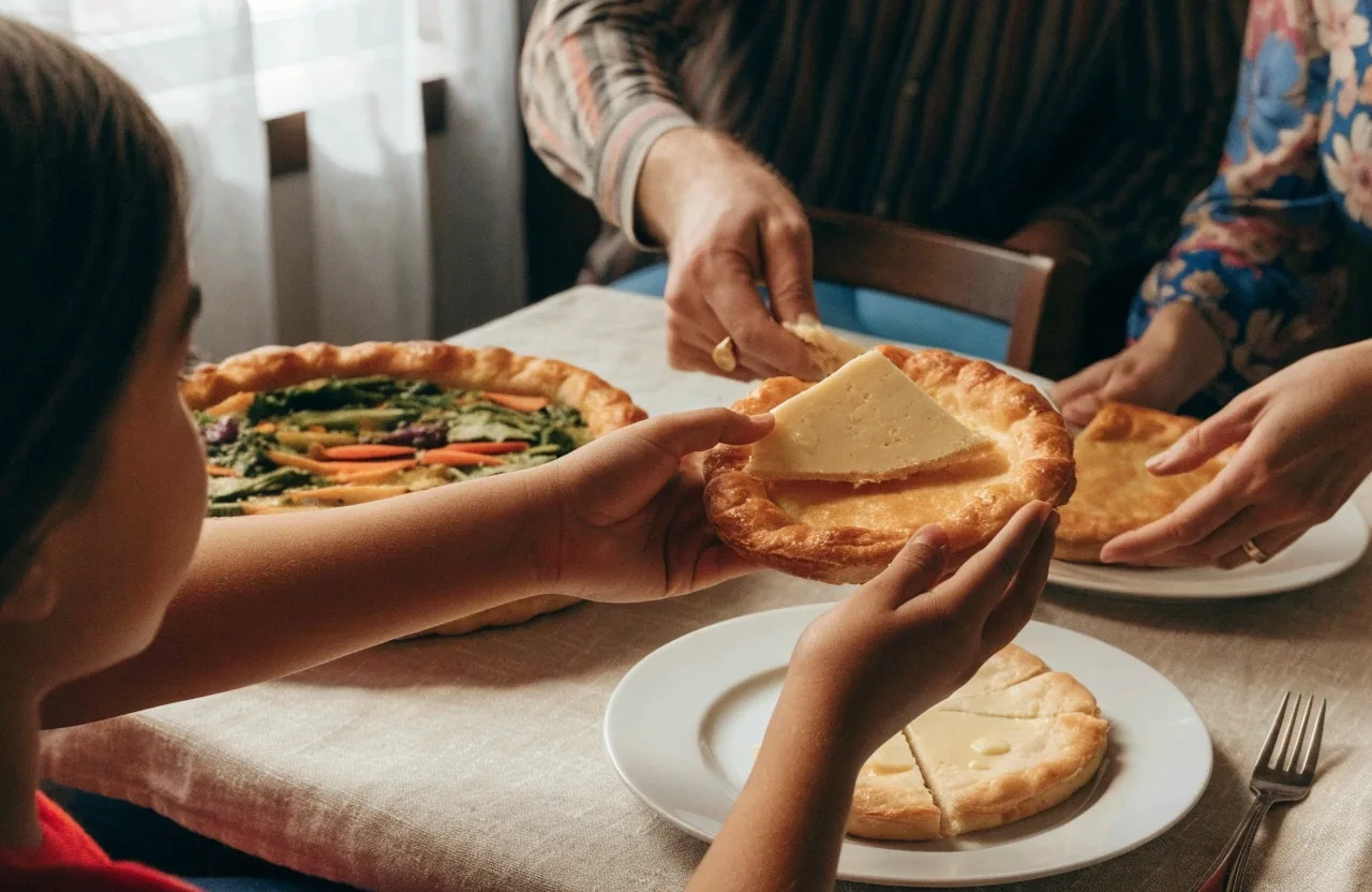 Family sharing plain and vegetable pizzas at a restaurant table